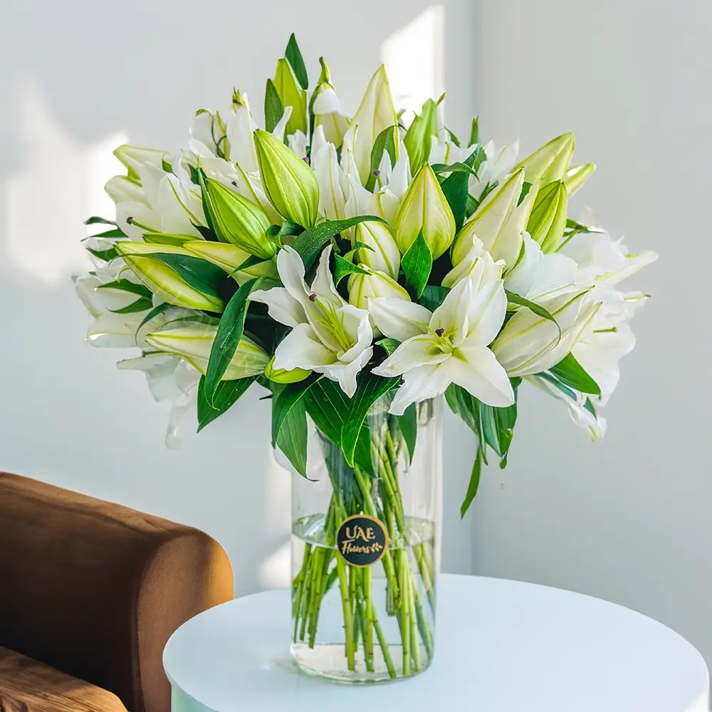 15 white lilies with green fillers in a glass vase