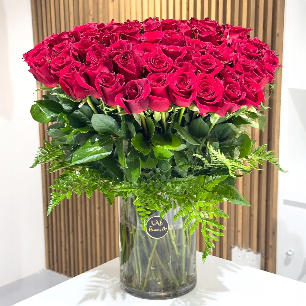 80 red roses with fillers in a glass vase