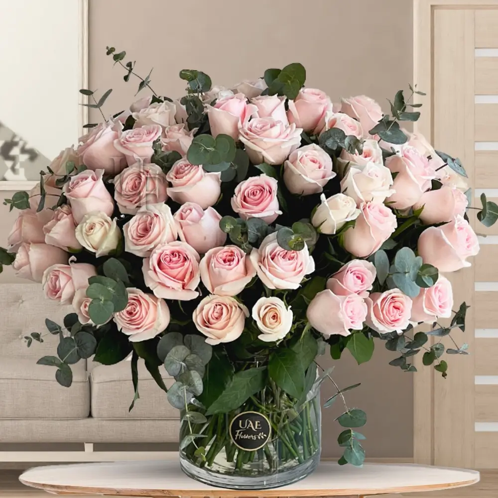 50 pink roses with eucalyptus leaves in a glass vase
