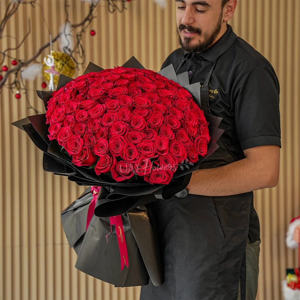 A romantic bouquet of 100 red roses in black wrapping paper tied with black ribbon