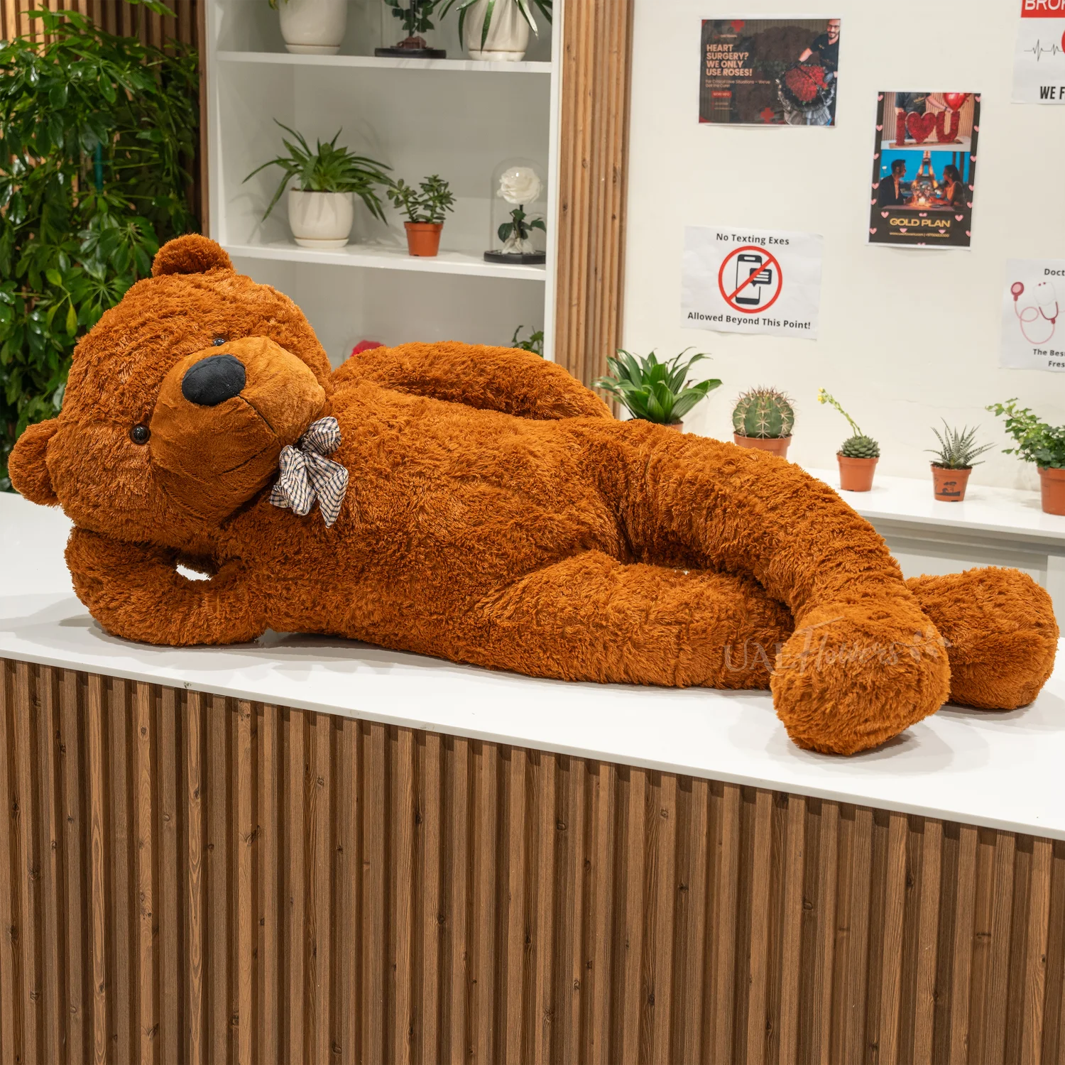 A large brown teddy bear sitting on a white table