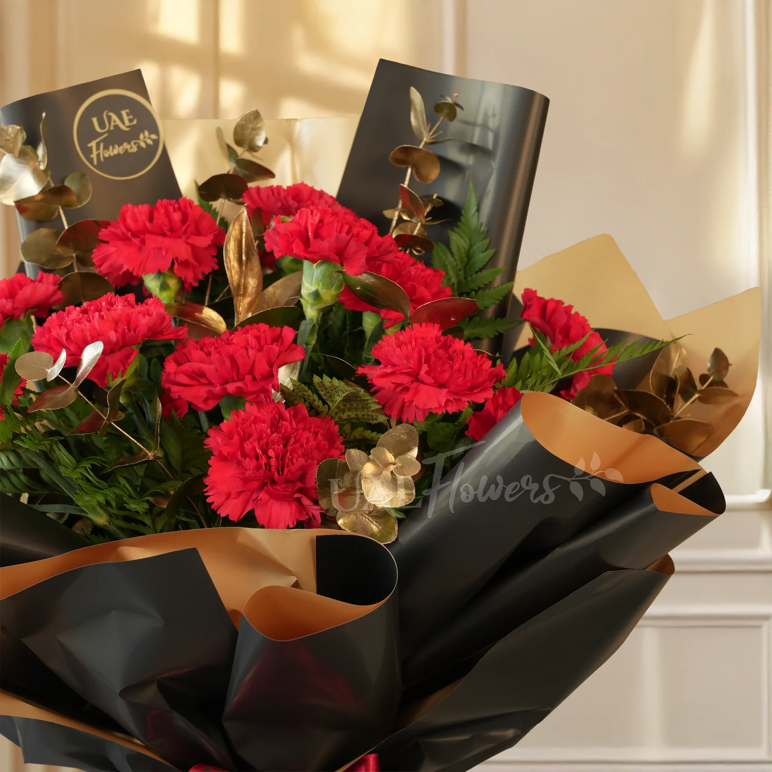bouquet of 10 red carnations with golden eucalyptus in black and gold wrap
