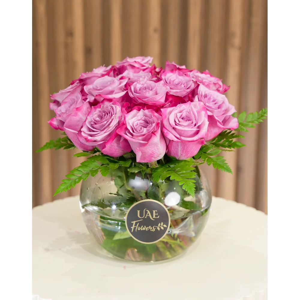 Clear glass vase with 15 purple roses and green fillers