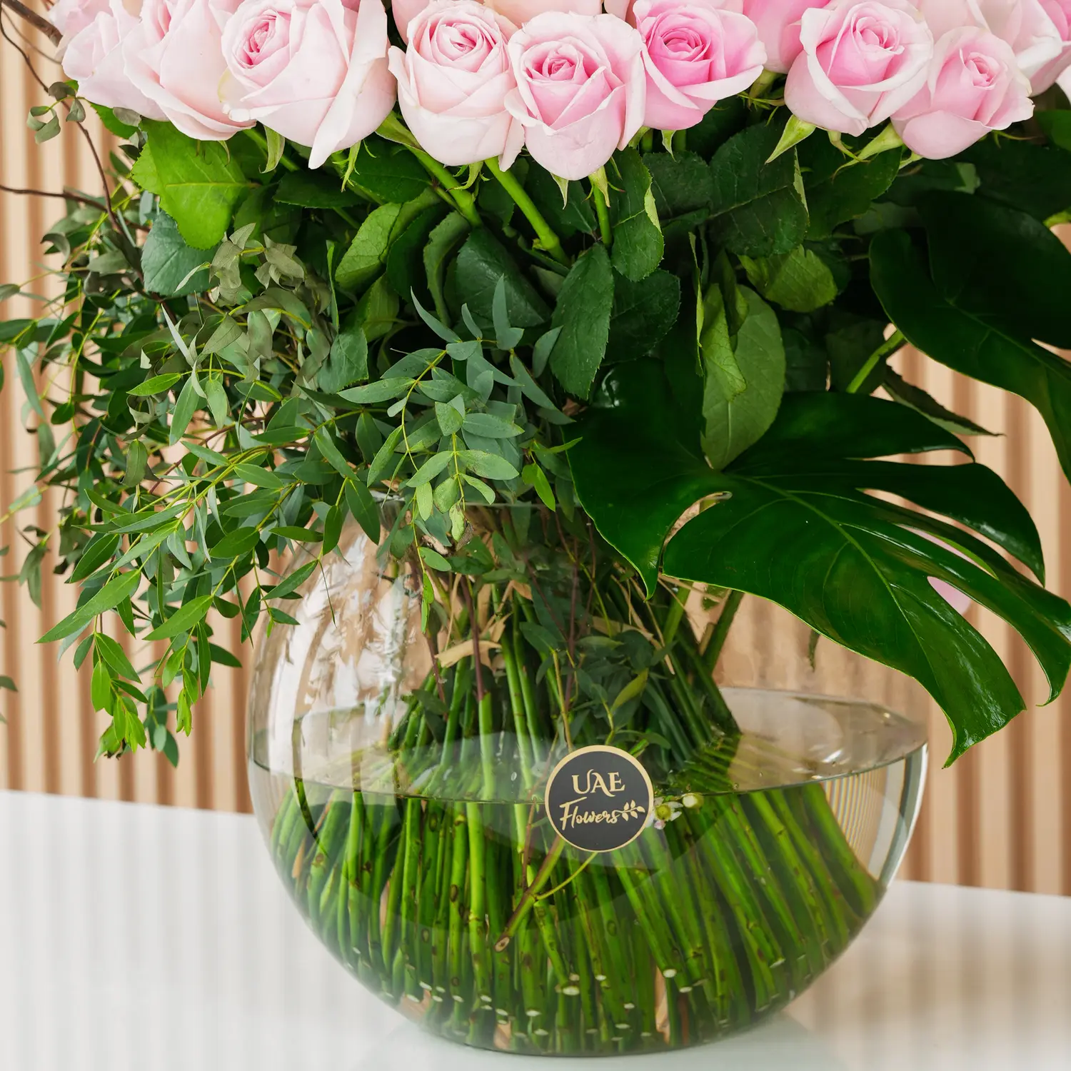 Pink Roses arrangement of 60 pink roses with lots of green fillers in a glass vase.