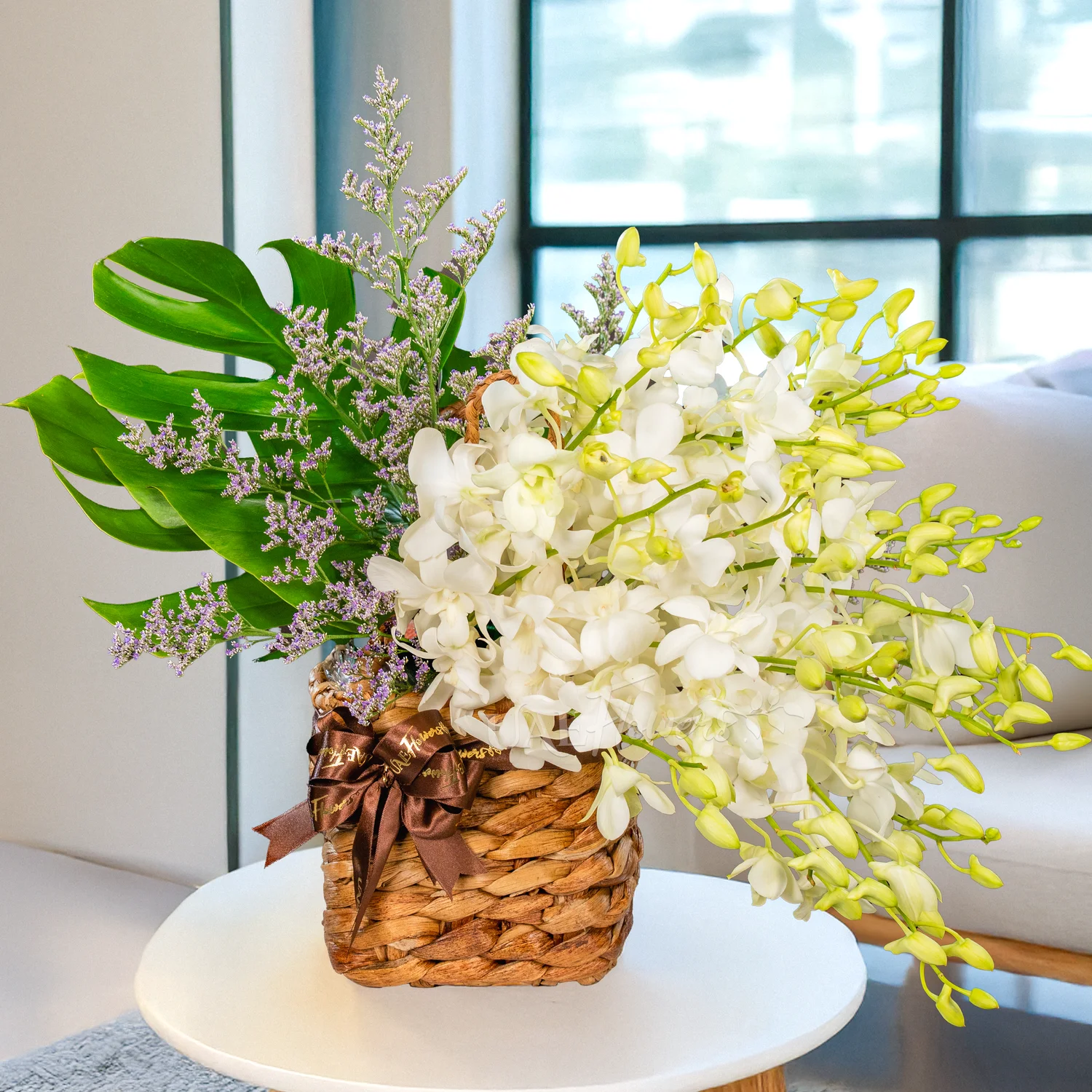 Handle basket with 20 white orchids, limonium, and green fillers, tied with elegant ribbons.