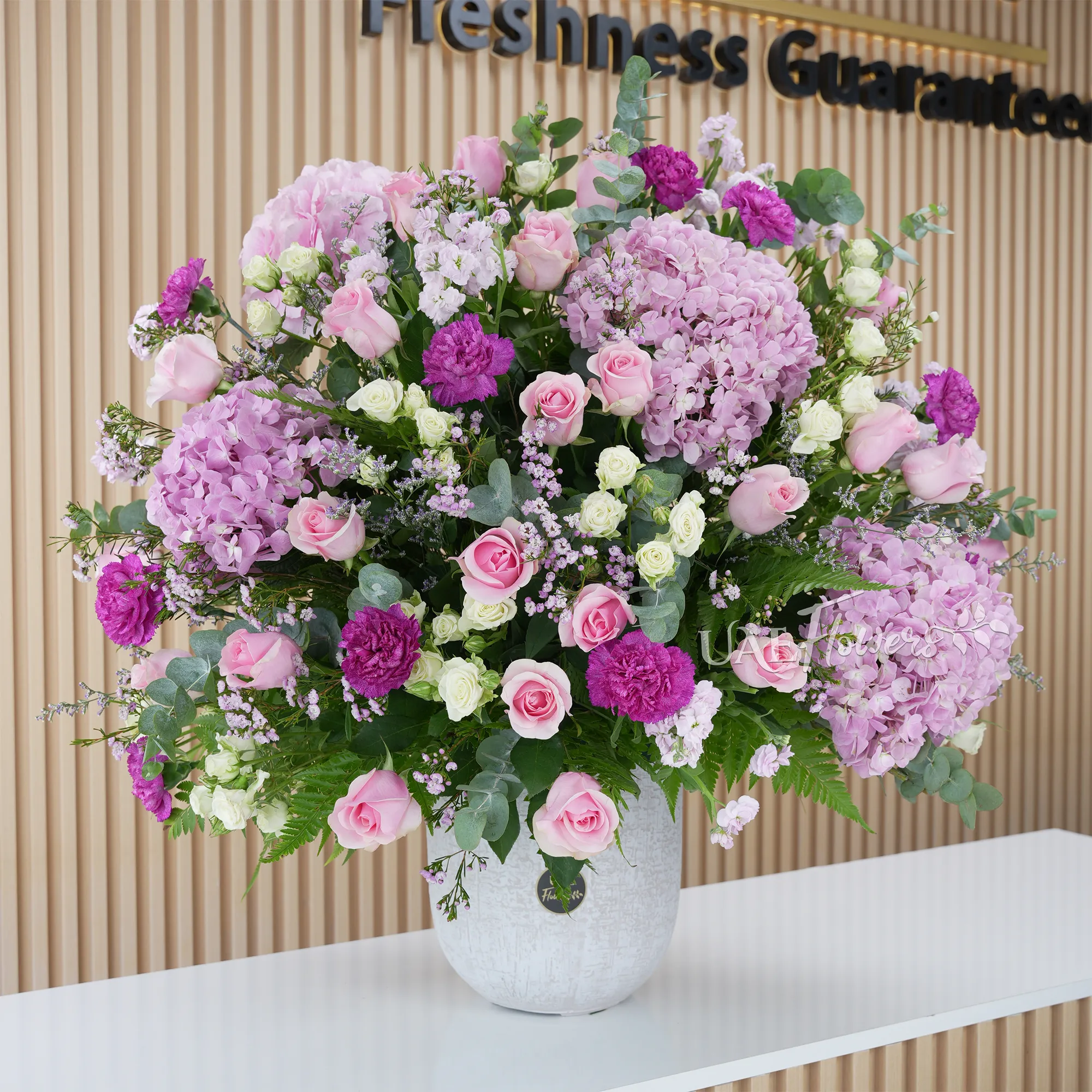 4 pink hydrangeas, 20 pink roses, 5 pink matthiola, and 7 green lisianthus with green fillers in a glass vase